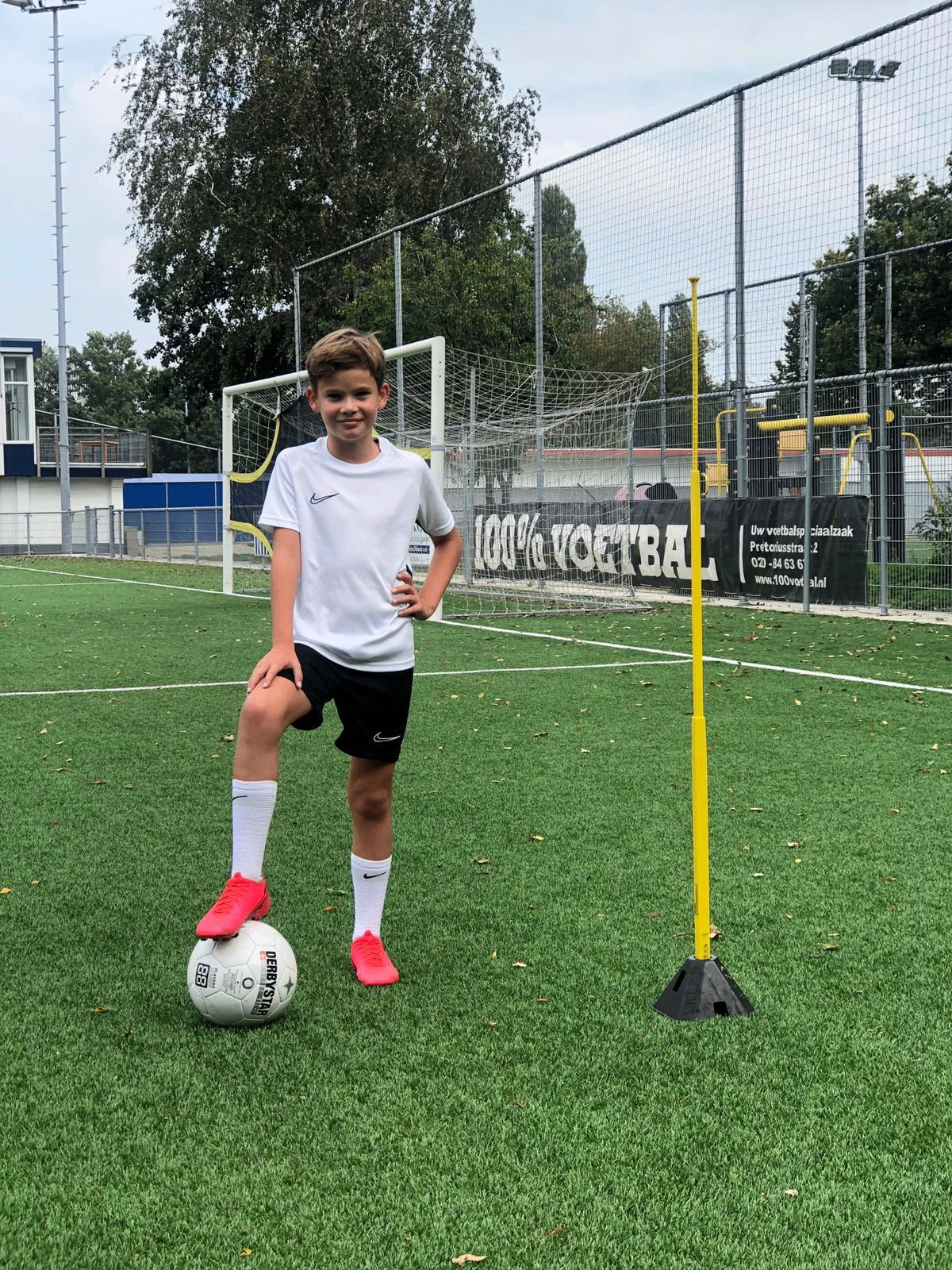 Jeugdspeler van DPC Academy poseert met bal op het trainingsveld.