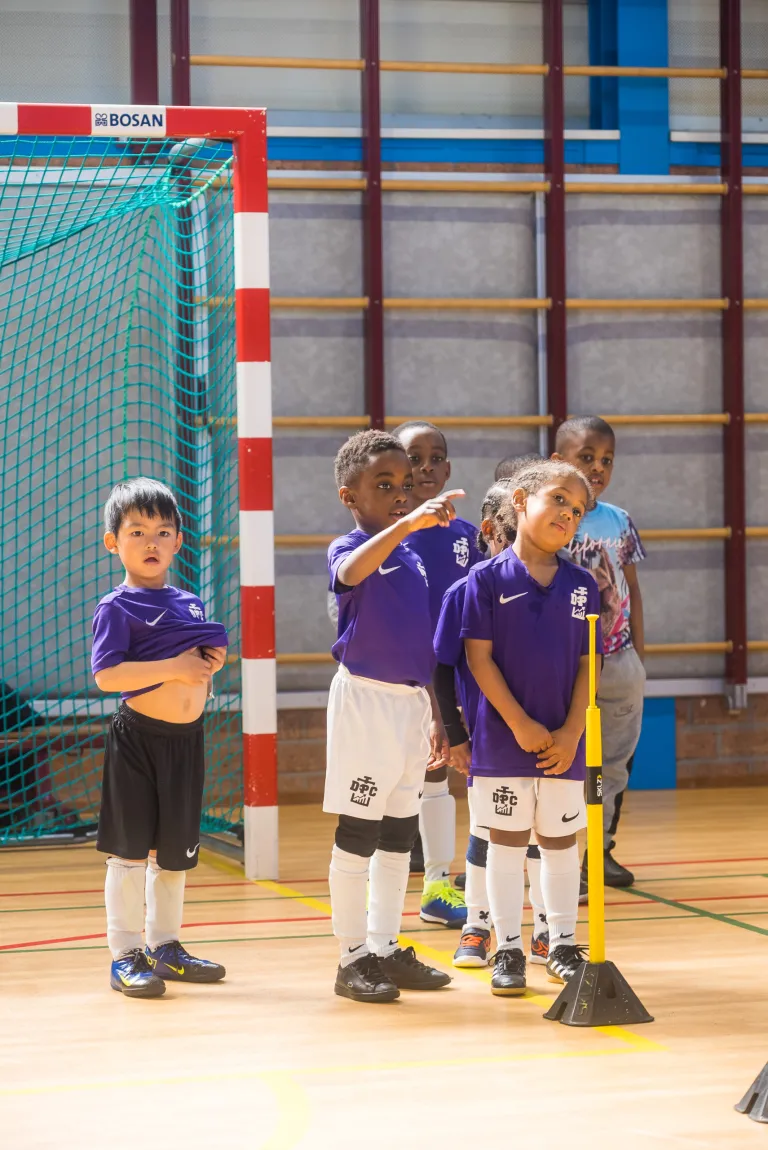 Kids Club-spelers van DPC Academy staan opgesteld in de sporthal voor een oefening.