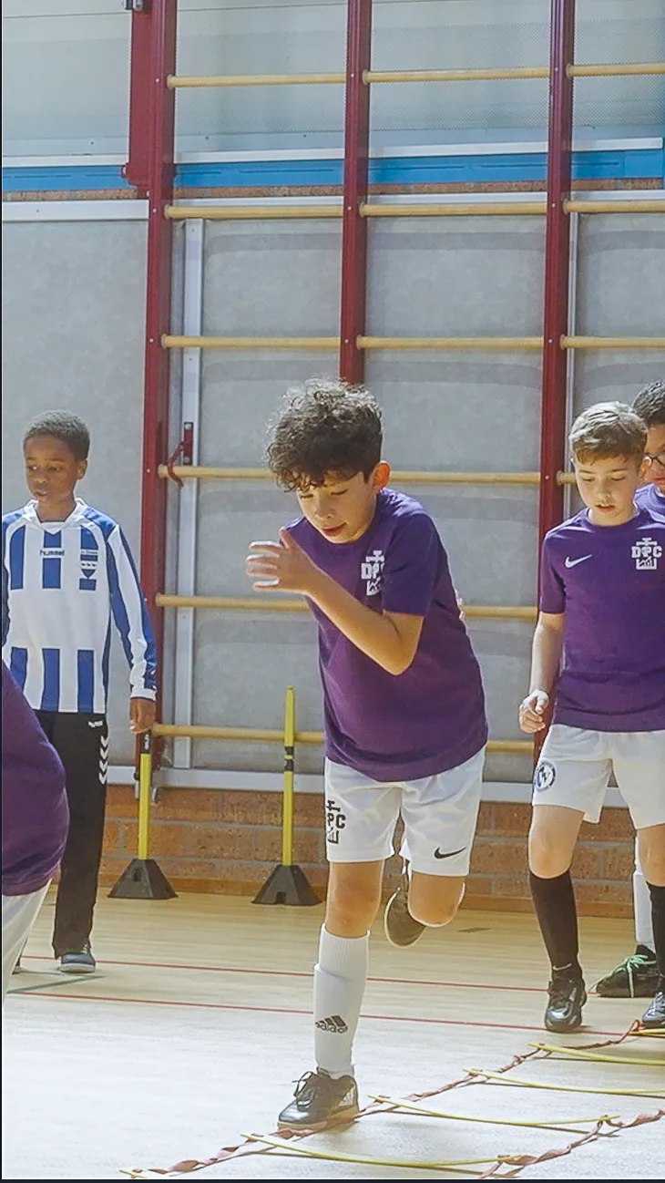 Spelers van DPC Academy werken samen aan een wendbaarheidsoefening in de sporthal.
